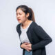 woman standing with stomach ache presses her hand her stomach 1